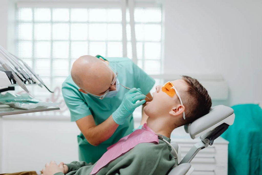 a dentist performing a dental check-up on the main with orange protective glasses
