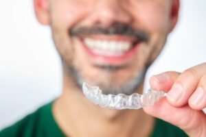 Man smiling while holding is Invisalign tray