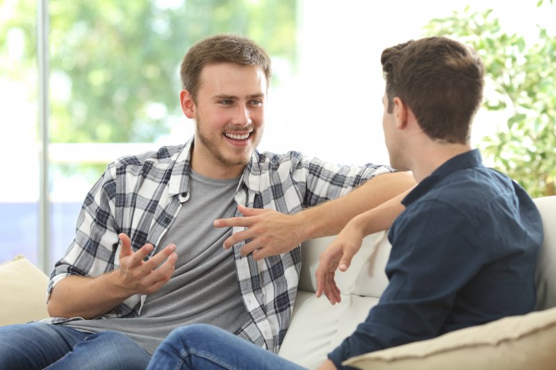 Two men speaking and smiling on a couch