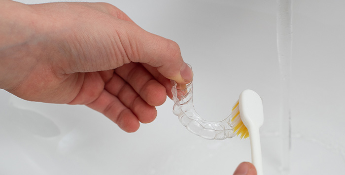 Patient cleaning clear aligner in sink