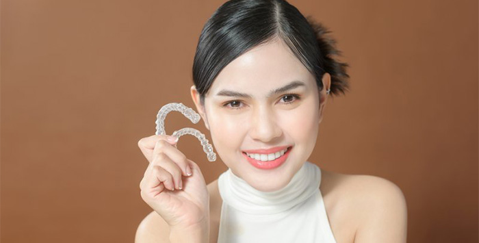 Smiling lady shows off Invisalign clear aligners