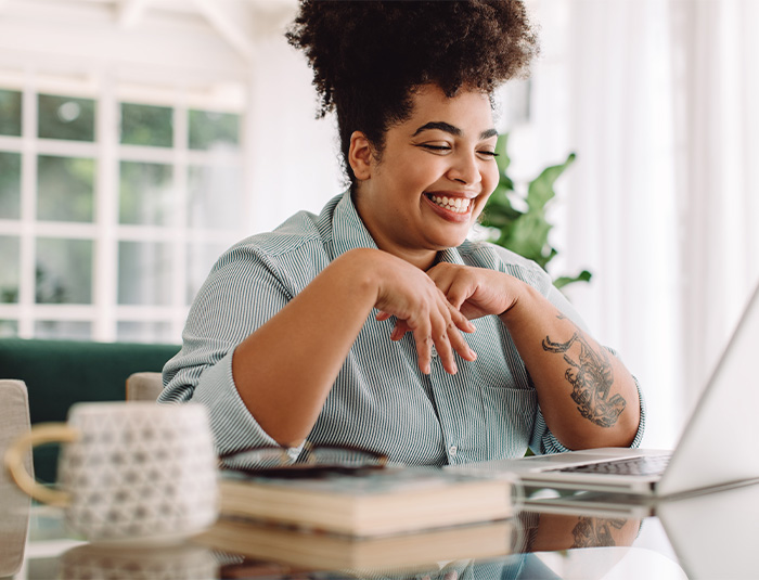 Woman smiling while working on laptop at home