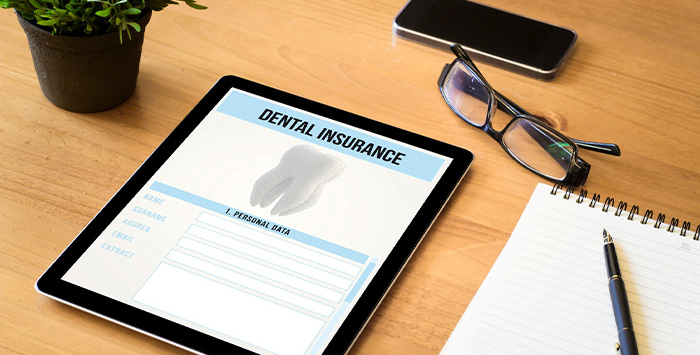 Dental insurance form on tablet next to desk supplies.