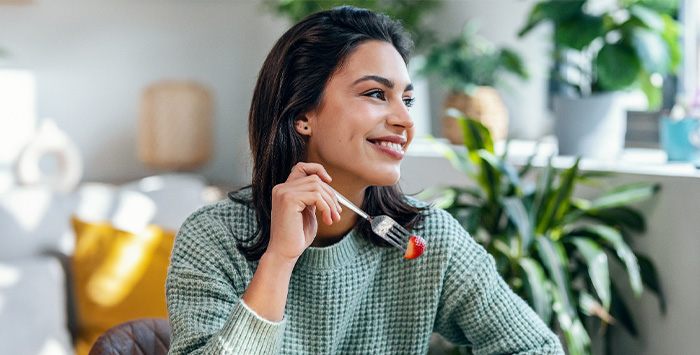 Woman smiling while eating healthy meal at home.