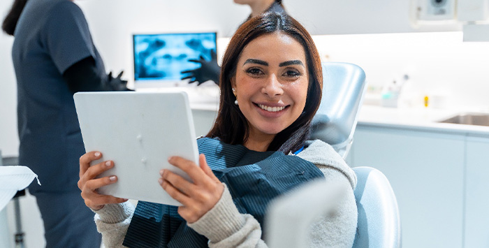 Woman smiling while holding handheld mirror.