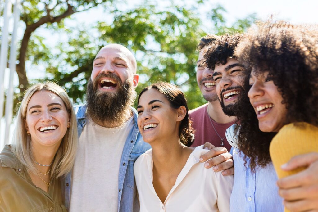 Group of people outside under trees smiling taking picture together