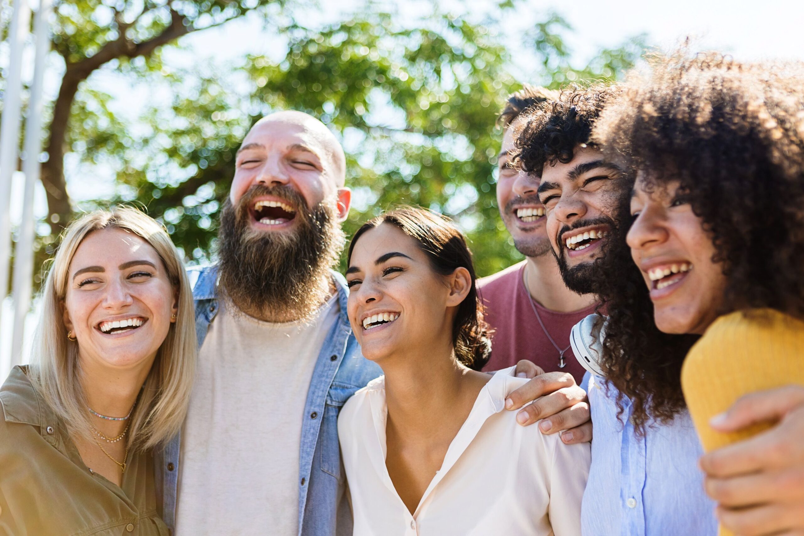 Group of people outside under trees smiling taking picture together